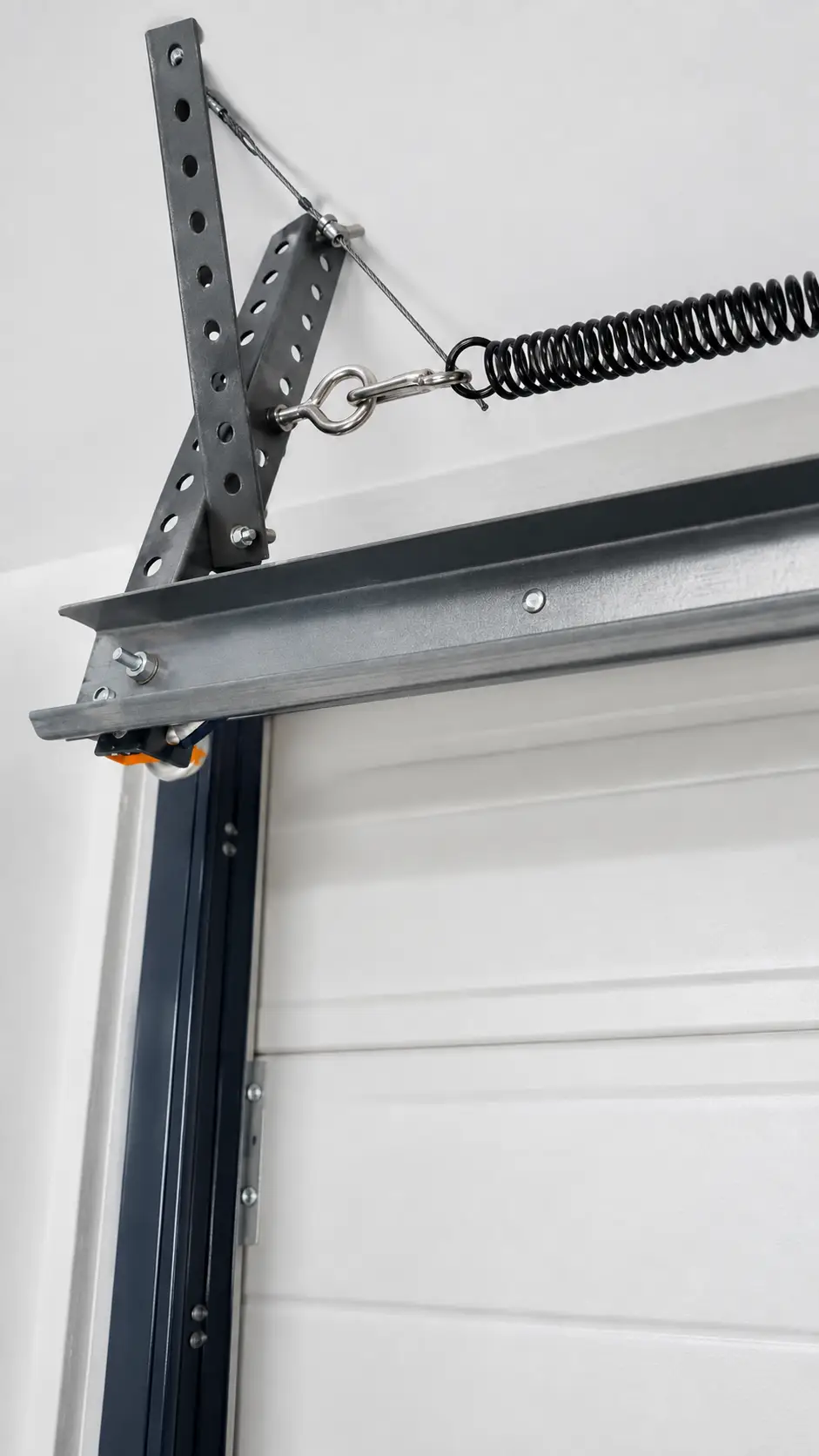 Garage door technician calibrating extension springs and fitting safety cables in Lawrence
